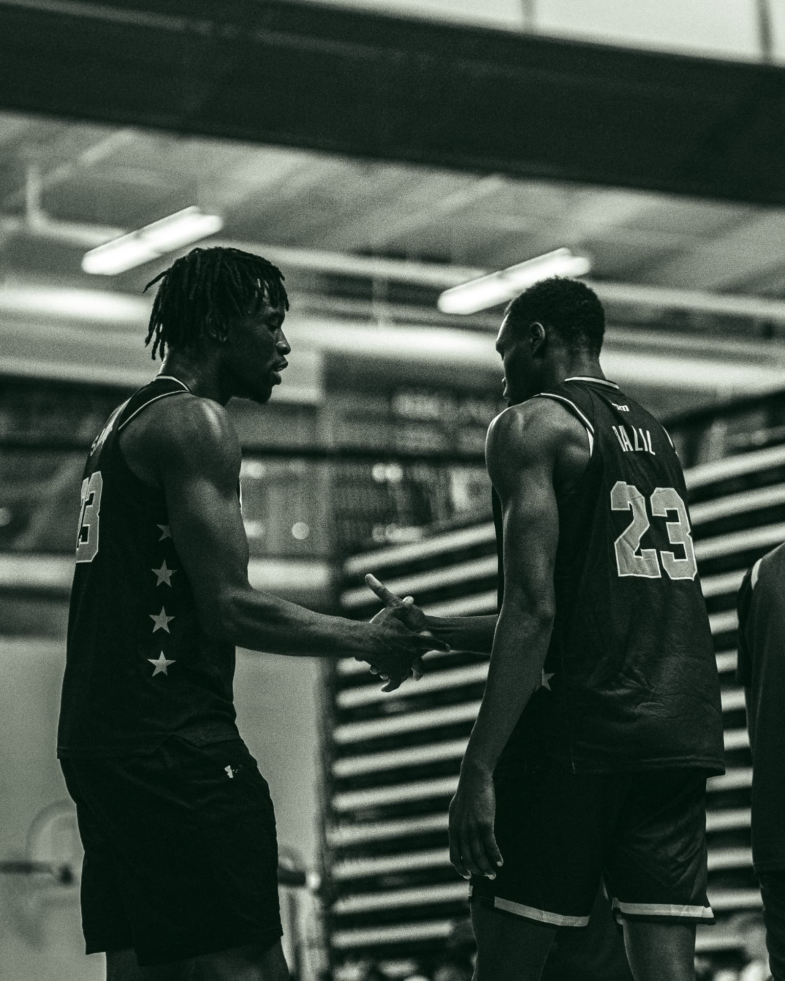 Two teammates shaking hands in black and white
